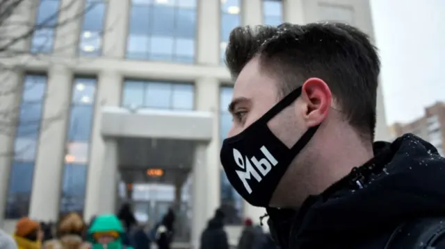 A Memorial International supporter, wearing a face masks with the logo of Russia's rights group, stand outside the Moscow City Court where a hearing over liquidation of Memorial's Human Rights Centre is ongoing, in Moscow on December 29, 2021