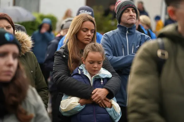 Woman hugging child at vigil in Milford