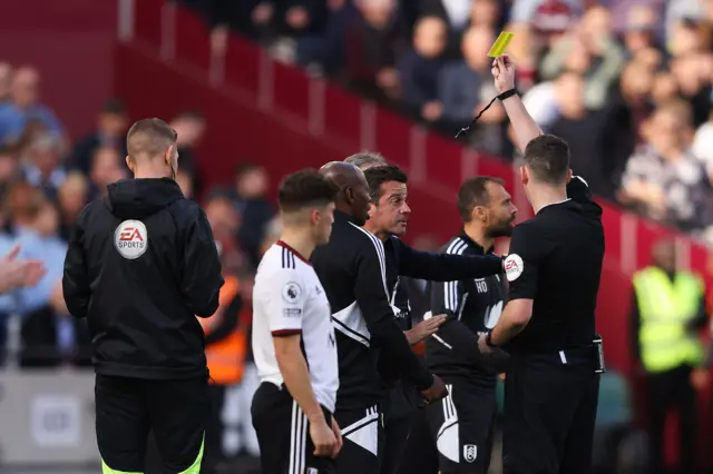 Referee Chris Kavanagh shows a yellow card to Marco Silva