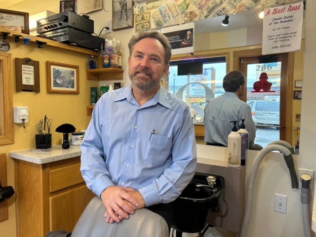 A photo of Mike, a barber in Kelispell, Montana, inside his barbershop.