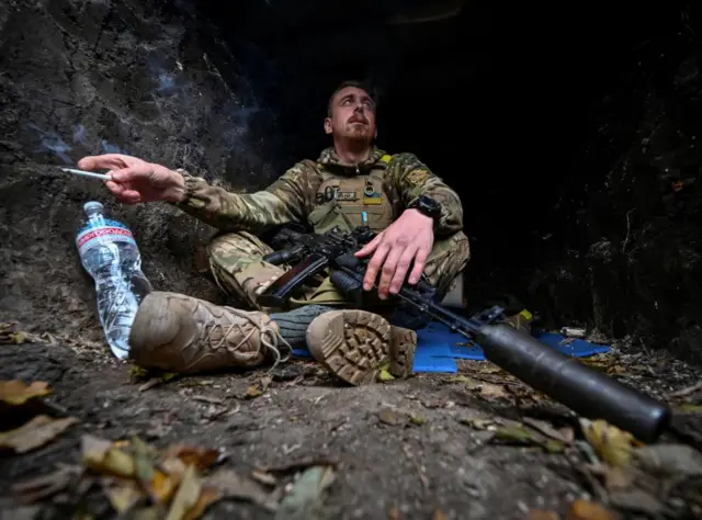 A Ukrainian serviceman rests in a trench