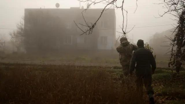 A Ukrainian serviceman walks with a chaplain next to a street, amid Russia’s attack on Ukraine, in a village near the newly recaptured city of Snihurivka,