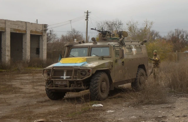 A Ukrainian troop stands next to a previously captured Russian armoured personnel carried in Blahodatne