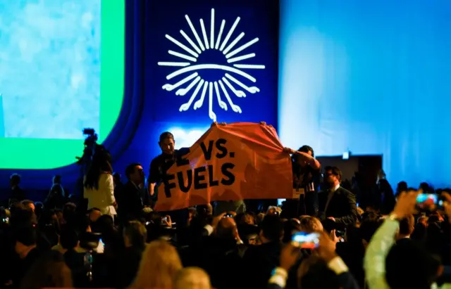 Protesters try to unfurl a banner during Biden's speech