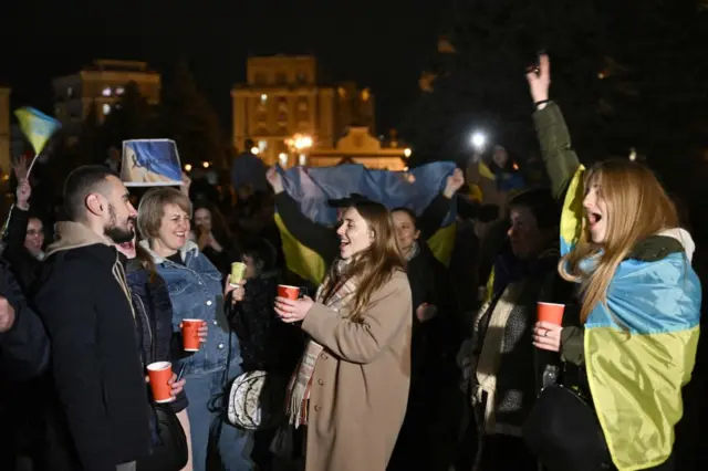 People holding red cups laugh together as they celebrate in Maidan Square