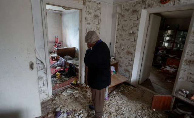 Nina Stovba stands inside the damaged house of her neighbour