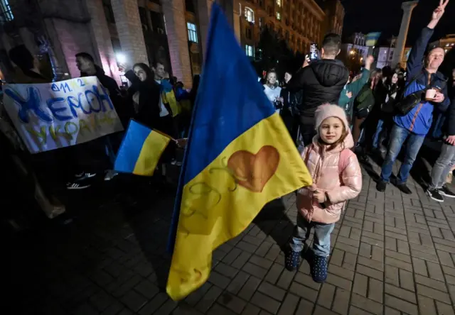 A child holds a Ukranian flag as people gather in Maidan Square in Kyiv to celebrate the liberation of Kherson on 11 November 2022