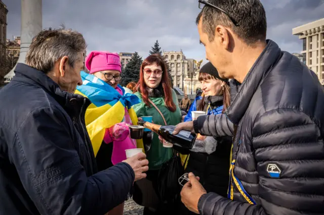 A man pours sparkling wine as part of celebrations in Kyiv's Independence Square