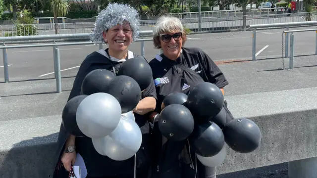 Two women with New Zealand shirts and black and silver balloons