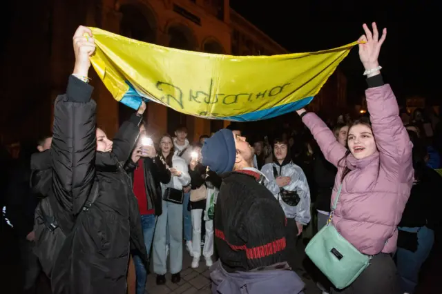 People hold a Ukrainian flag celebrating the liberation of Kherson from Russian occupiers in central Kyiv