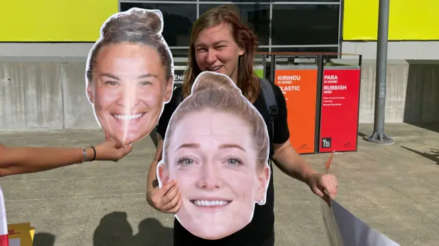 Sophie holding up pictures of Portia Woodman and Hollie Davidson’s face