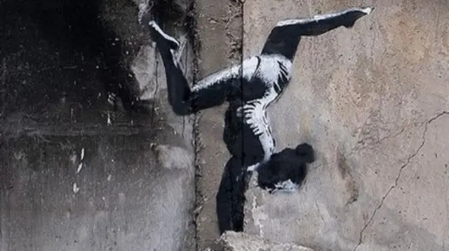 Graffiti of a gymnast doing a handstand painted on a destroyed building in Borodyanka