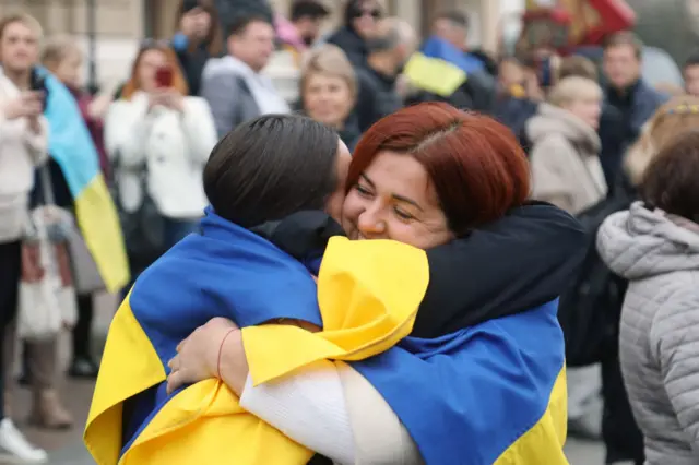 Residents of Kherson who are temporarily living in Odesa wore Ukrainian flags as they were pictured embracing in front of The Odesa National Academic Opera and Ballet Theatre