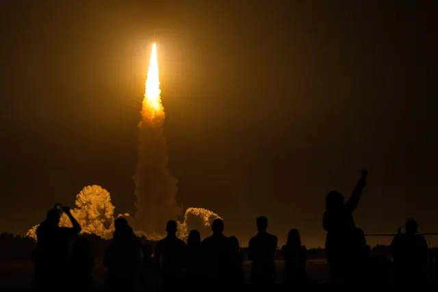 Spectators cheer as the Artemis I unmanned lunar rocket lifts off from launch pad 39B at NASA's Kennedy Space Center in Cape Canaveral, Florida, on November 16