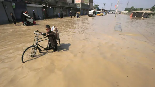 A boy wades through a flooded area following heavy rains in Nowshera District, Khyber Pakhtunkhwa province, Pakistan, 30 August 2022.