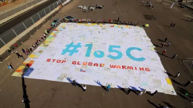 Sign filmed from above that reads 1.5C stop global warming