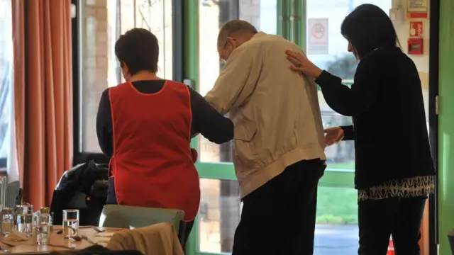 Care home staff helping a man