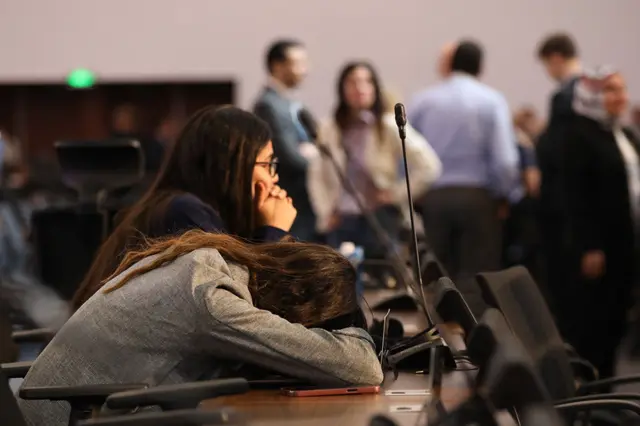 delegate rests head on a desk in exhaustion