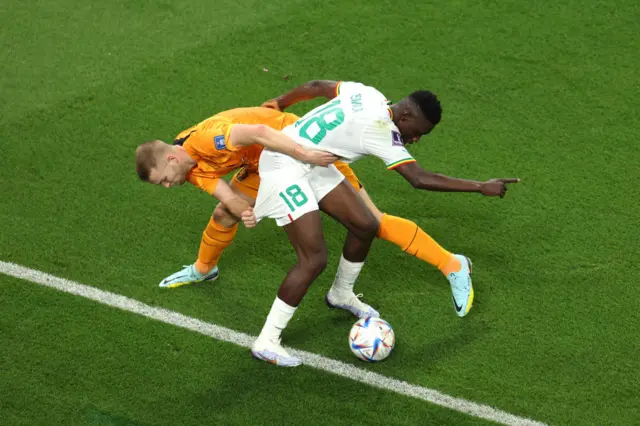 Ismaila Sarr is wrestled to the ground by Mathis De Ligt