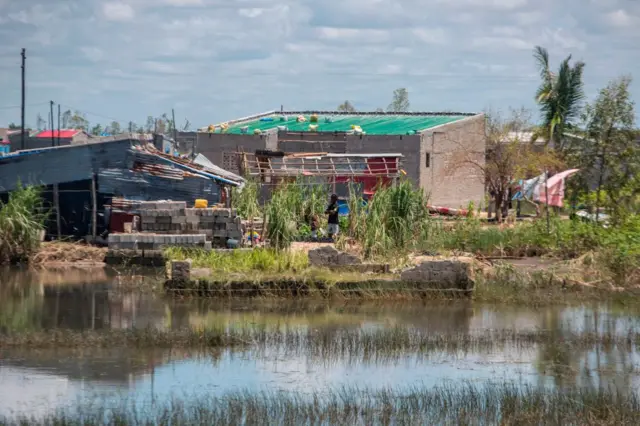 A man stands next to a house in an area flooded by the rains of cyclone Eloise in the Chinamaconde community of the Dondo district of Beira last year