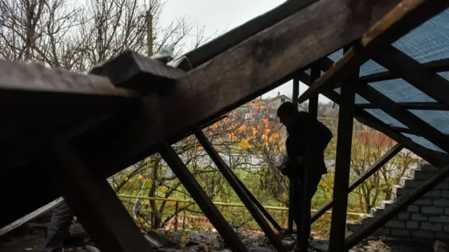 A man repairs the roof of damaged house he returned to after combat action in Posad-Pokrovske village, Kherson region