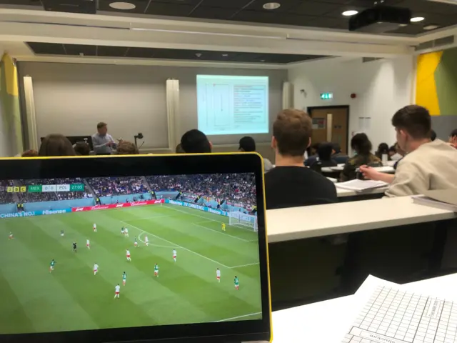 A fan watches Mexico v Poland in their lecture: Tom: Game on mid Engineering lecture! Uppa Polska!