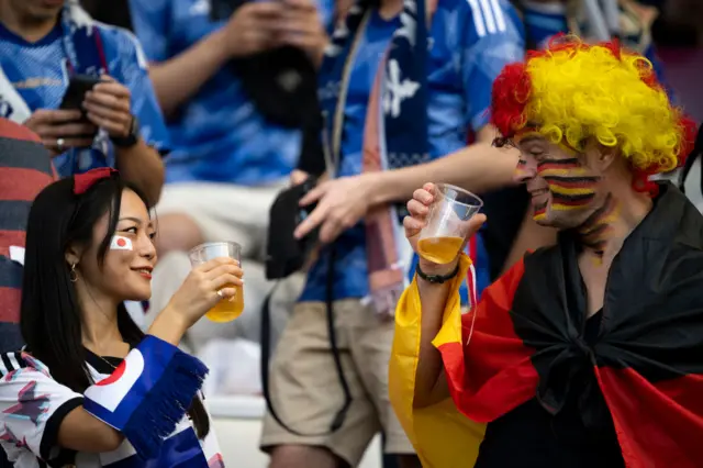 A Japan and Germany fan holding a non-alcoholic beer