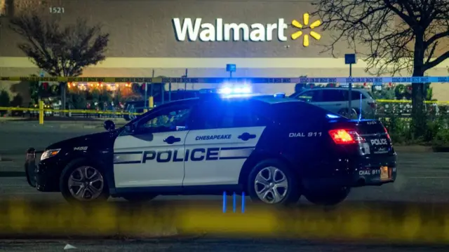 A police car with flashing blue lights parked at night outside Walmart in Chesapeake, Virginia