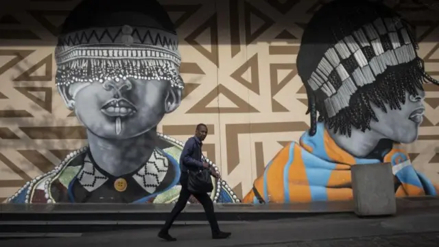 Mandatory Credit: Photo by KIM LUDBROOK/EPA-EFE/REX/Shutterstock (13636193b) A pedestrian enjoys his walk in Jewel City in Johannesburg, South Africa, 24 November 2022. The area has been revitalized as a process of re-development of the once downtrodden downtown district. The effort brought safety, business, more tourists and a lot of art and color into the area.