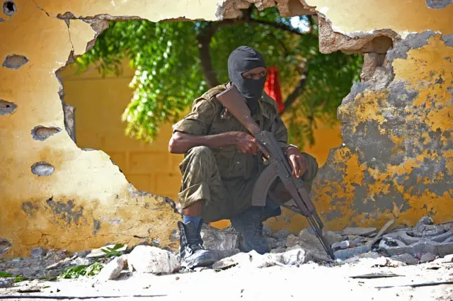 A Somali soldier stands guard next to the site where Al Shabab militants carried out a suicide attack