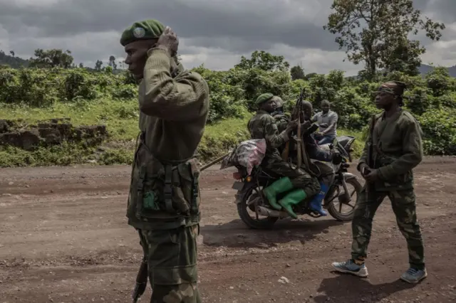 A motorcyclist carries soldiers as others patrol the area in Kibumba that was attacked by M23 rebels in clashes with the Congolese army, near the town of Goma in eastern Democratic Republic of Congo, June 1, 2022