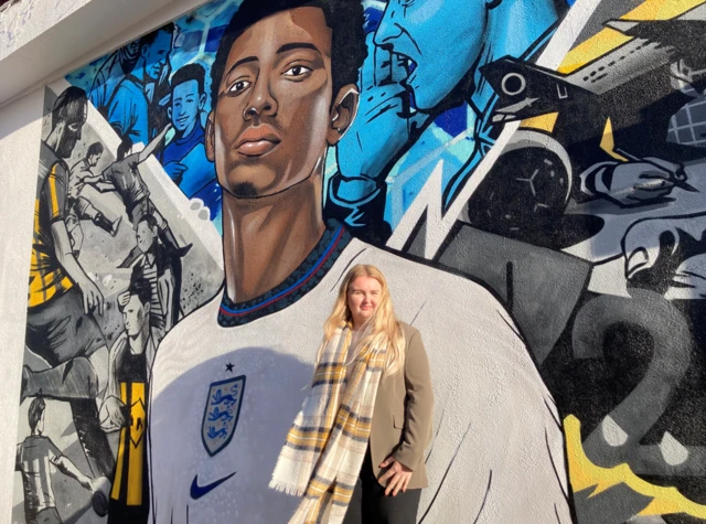 Amye Evitts in front of a mural of Jude Bellingham in an England kit