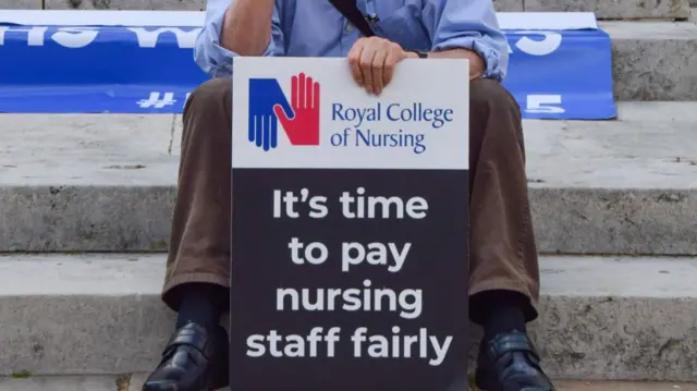 A protester holds a placard calling for fair pay for NHS nurses during a protest outside Westminster last year