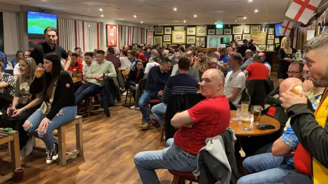 A crowded pub watches the game