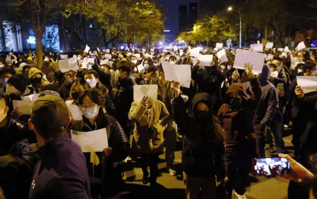 People hold up blank sheets of paper during a protest in Beijing on Sunday night