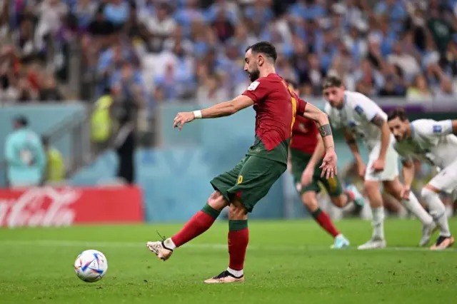 Portugal's midfielder #08 Bruno Fernandes (L) scores his team's second goal from the penalty spot during the Qatar 2022 World Cup Group H football match between Portugal and Uruguay at the Lusail Stadium in Lusail, north of Doha on November 28