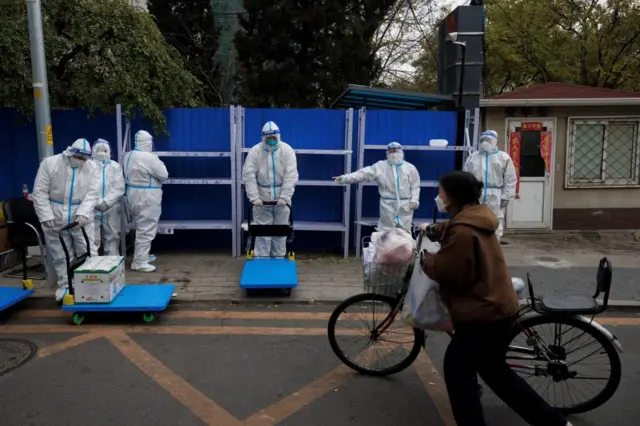 A woman delivers food to a residential compound under lockdown as Covid outbreaks continue in Beijing