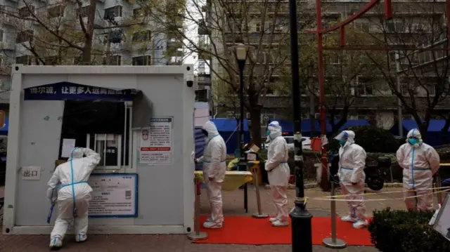 Epidemic-prevention workers in full protective suits in protective suits line up to get swab tested as outbreaks of coronavirus disease (COVID-19) continue in Beijing