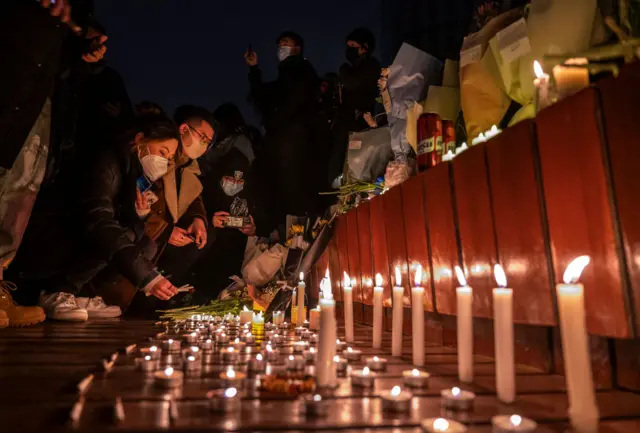 At a vigil, people lit candles and laid flowers for the victims of the Urumqi flats fire