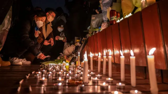 Protesters light candles and leave cigarettes at a memorial during a protest against Chinas strict zero COVID measures on November 27, 2022 in Beijing, China