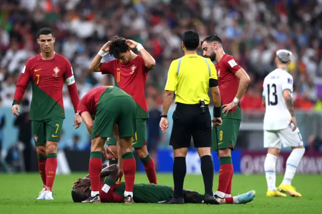 Nuno Mendes of Portugal is attended to by teammates during the FIFA World Cup Qatar 2022 Group H match between Portugal and Uruguay at Lusail Stadium on November 28, 2022 in Lusail City, Qatar.