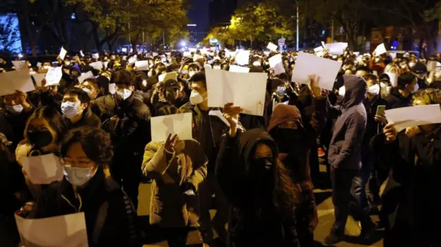 Protesters march while holding blank white pieces of paper