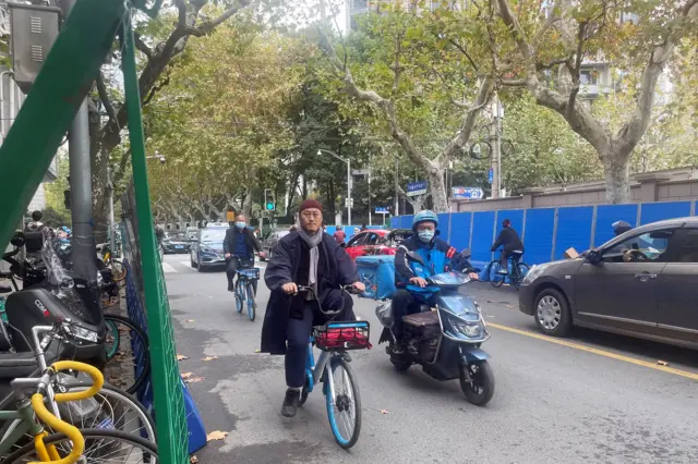 People ride past barriers set up along a road, where protests against coronavirus disease (COVID-19) curbs took place following the deadly Urumqi fire, in Shanghai, China November 28, 2022