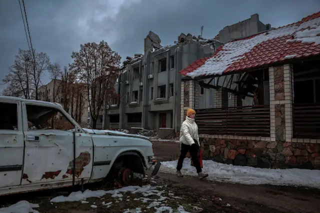 A person walking on a snowy street among destroyed buildings from the war