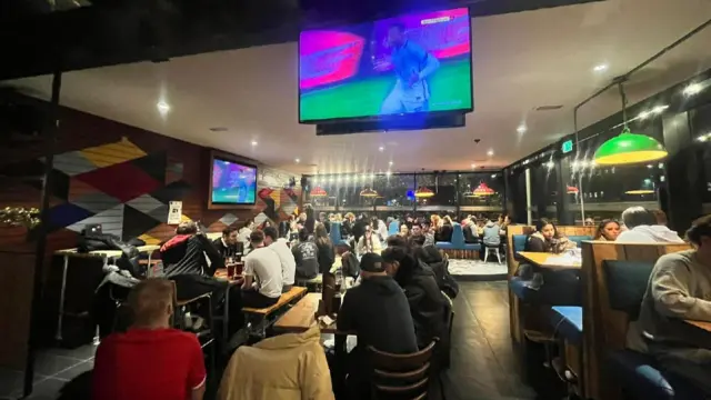 Students crowd around the many screens around their student union bar in Lincoln