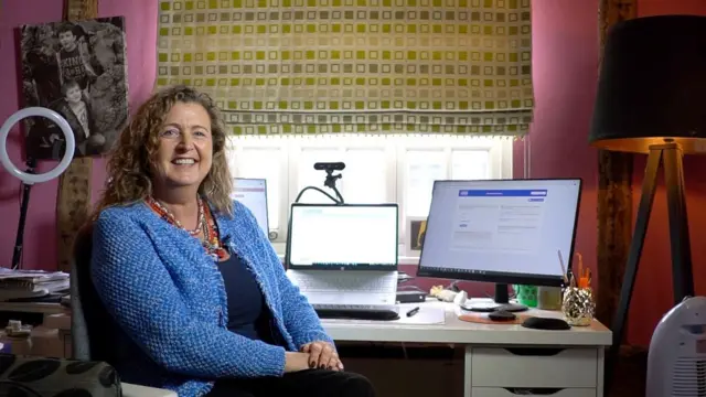 Sally Mitchell sitting at her desk at home