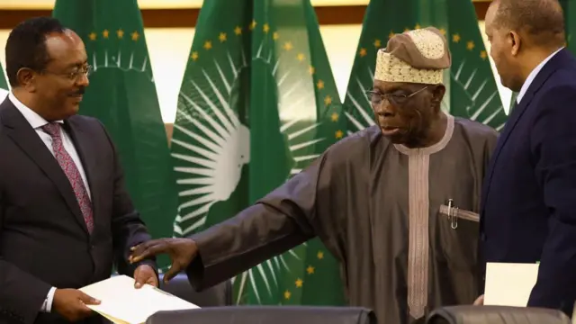 Former Nigerian president and African Union envoy Olesegun Obasanjo gestures to Ethiopian government representative Redwan Hussien and Tigray delegate Getachew Reda after signing the AU-led negotiations to resolve the conflict in northern Ethiopia, in Pretoria , South Africa, November 2, 2022