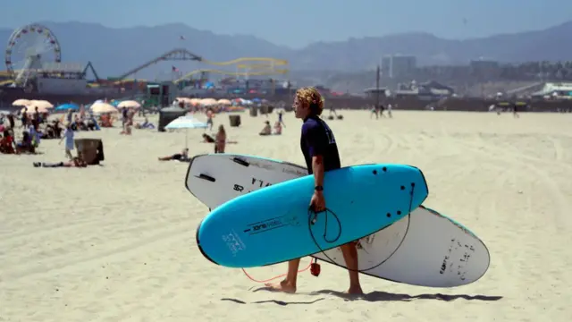 A surfer carrying boards in LA