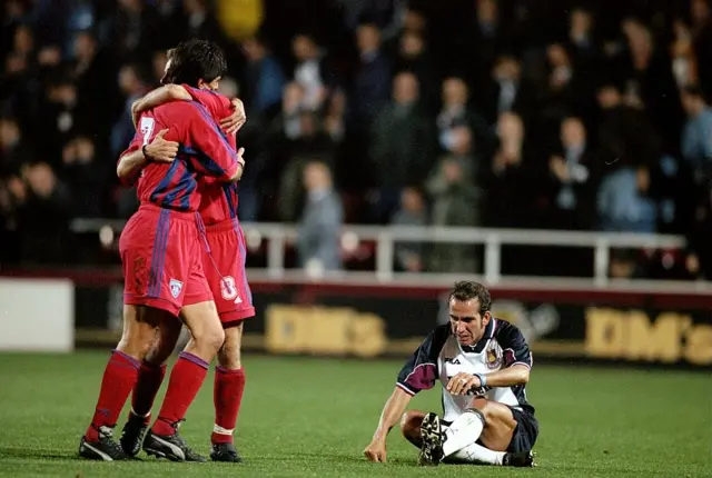 Paolo di Canio sets on the turf while two Steaua Bucharest players celebrate in 1999