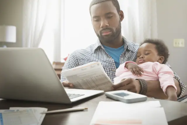 Man with baby poring over bills